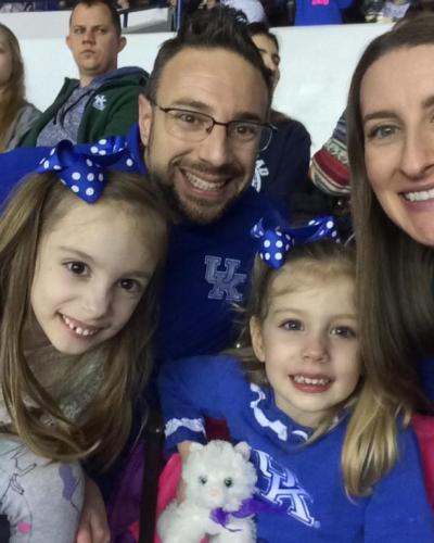 A family of four wearing University of Kentucky apparel smile for a photo at an event.